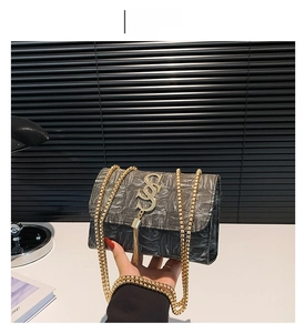 Détail du sac bandoulière plissé noir avec logo S doré et bandoulière chaîne