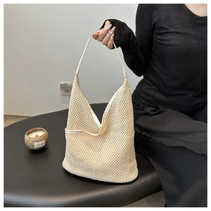 Détail d'un sac seau en maille tressée beige avec motif ajouré fin et bandoulière