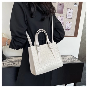 Detail of white woven crossbody tote bag featuring metal rivets and adjustable strap