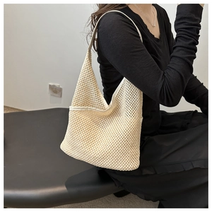 Détail du sac bandoulière en maille crème montrant la texture tressée et la lanière