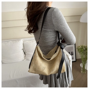 Détail du sac cabas en paille tissé à la main avec bandoulière noire et texture naturelle