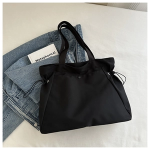 Detailed top view of black canvas tote bag with drawstring texture and snap button closure