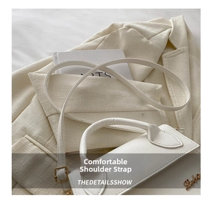 Detail of white PU leather crossbody bag with adjustable strap and golden logo