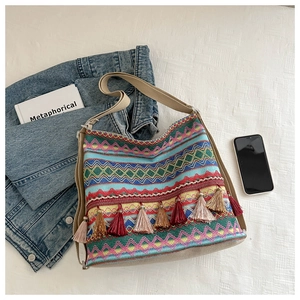 Detail of bohemian woven tote bag showing colorful tassels and geometric diamond patterns