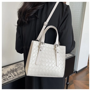 Detail of white woven textured tote bag featuring silver hardware and adjustable strap