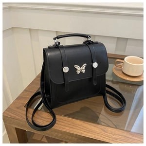 Detail view of mini black leather backpack with silver butterfly accent and top handle