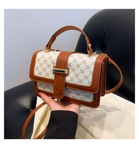 Détail du sac bandoulière vintage avec motif monogramme et boucle en métal doré