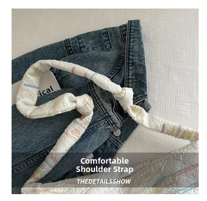 Detail of white textured shoulder bag strap featuring colorful decorative stitching accents