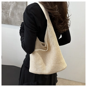 Détail du sac fourre-tout tissé crème montrant la texture en maille et le style porté épaule