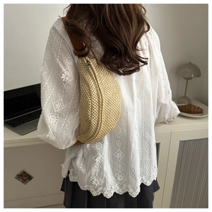 Détail du sac banane beige tissé à la main porté en bandoulière sur le mannequin