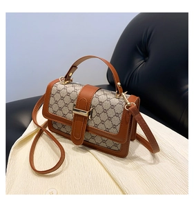 Détail de la toile vintage, des finitions en cuir marron et du fermoir en métal doré du sac