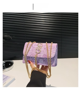 Détail de la pochette violette plissée avec boucle dorée en S et bandoulière chaîne