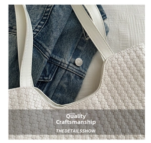 Close-up of white woven texture and cross-stitch craftsmanship on a tote shoulder bag