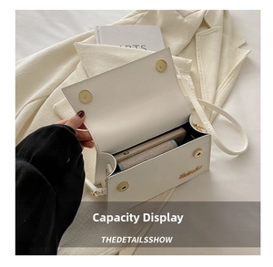 Detail view of the spacious interior of a white flap shoulder bag with a gold clasp