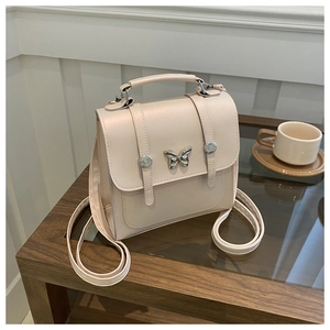 Retro cream butterfly buckle messenger bag on a wooden table in a cozy setting