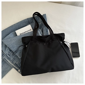 Detail of black nylon tote bag showing drawstring closure and metallic snap button