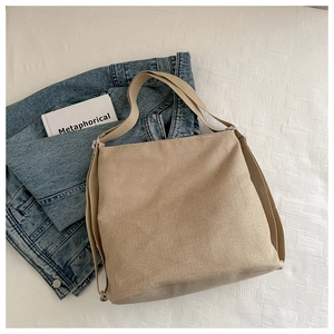 Detail of beige canvas tote bag with wide fabric straps and diagonal woven texture