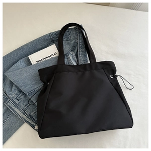 Flat lay of black nylon tote bag with drawstring detail and stylish denim jacket