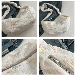 Detailed close-up of quilted floral crescent bag with wavy embroidery and metal zipper