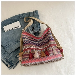 Macro view of bohemian knit tote bag with colorful geometric patterns and fringe detail