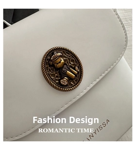 Detailed close-up of white leather bag with gold vintage bear clasp and Anyissa logo