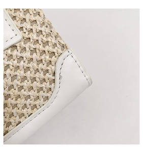 Gros plan sur le tissage de paille et les coutures en cuir blanc du sac bandoulière