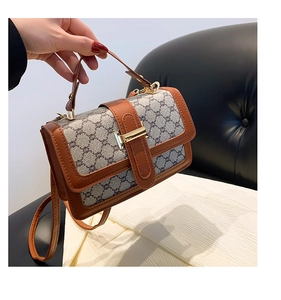 Gros plan sur les finitions en cuir marron et la toile grise texturée du petit sac carré