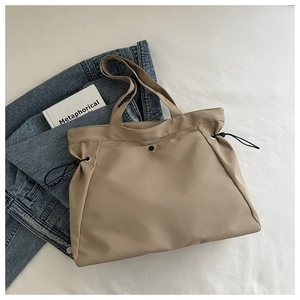 Detail of khaki waterproof nylon tote bag with black drawstring and wide shoulder strap