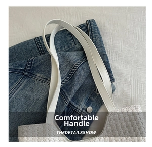 Detail of the white woven fabric texture and smooth leather handle on a casual tote bag