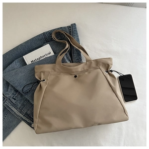 Detail of beige nylon tote bag with adjustable side drawstrings and large capacity