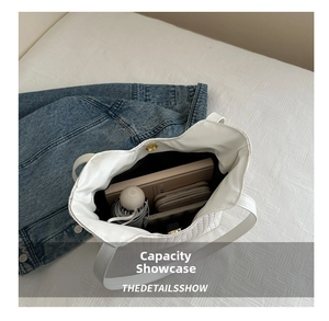 Macro view of white quilted tote bag interior showing capacity for umbrella and notebook