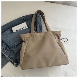 Detail of khaki tote bag featuring waterproof nylon texture and side drawstring accents