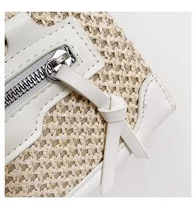 Détail du sac en paille tissée avec garniture en cuir blanc et fermeture éclair argentée