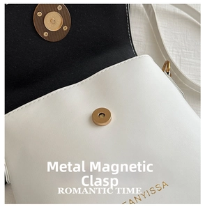 Detailed close-up of white leather handbag featuring gold magnetic buckle and gold logo
