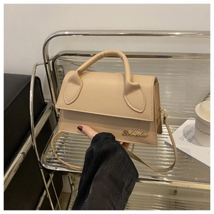 Detailed close-up of a beige structured shoulder bag with golden logo and leather texture