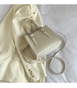 Detailed view of cream woven tote bag with adjustable strap on a neutral background
