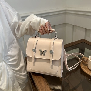 Elegant beige butterfly flap crossbody bag with metal buckle and top handle straps