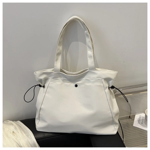 Detail view of large white canvas tote bag with side drawstrings and matte waterproof texture