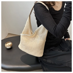 Détail de la texture en maille tissée blanc cassé d'un sac seau bandoulière chic d'été