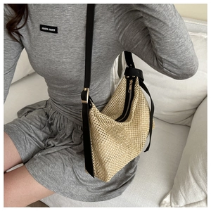 Détail du sac hobo en paille tressée avec bandoulière en cuir noir et fermeture