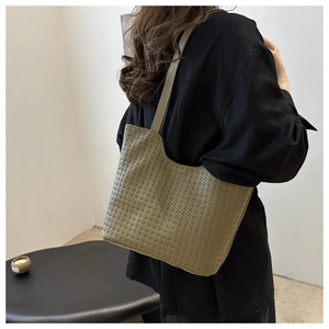 Detail of moss green woven tote bag showing crossbody texture and shoulder strap fit