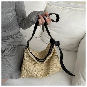 Détail du sac cabas en paille tissée avec anses en cuir noir et fermeture éclair