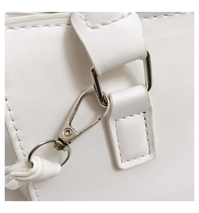 Détail du fermoir mousqueton argenté et de l'anneau en D sur un sac en cuir blanc avec coutures