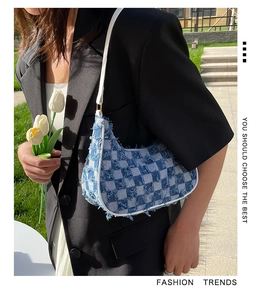 Détail du sac baguette en jean à carreaux bleus avec bords effilochés et lanière