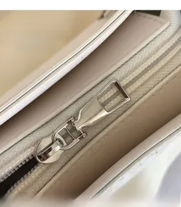 Close-up of the smooth silver zipper and premium leather texture on white square bag