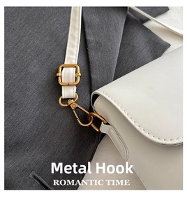 Close-up of bronze hardware hook and fine white leather texture on a shoulder bag