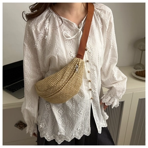 Detail of woven straw sling bag with crescent shape and brown canvas strap for women