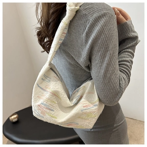 Vue détaillée d'un sac en nylon blanc avec broderies vagues colorées et texture plissée
