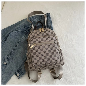 Detail of grey monogram backpack with double gold zippers and textured woven straps