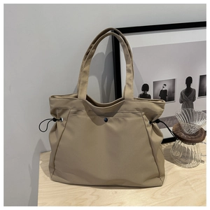 Detail of khaki canvas tote bag with drawstring side and magnetic button on wooden table